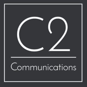 A square logo with a dark background featuring the text "C2 Communications" in white. The "C2" is centered and large, occupying the top part of the logo, while "Communications" is smaller and placed below a horizontal line. The logo is bordered by a thin white line.